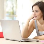 High school student looking at laptop screen at home