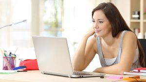 High school student looking at laptop screen at home