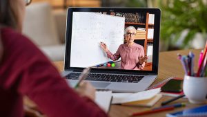 Laptop screen with female teacher pointing at whiteboard