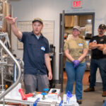 Brewing course instructor shows students professional brewing equipment.