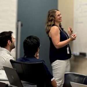 Julie Harris writing on whiteboard with team members looking on.